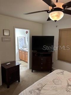 carpeted bedroom featuring ceiling fan and ensuite bath