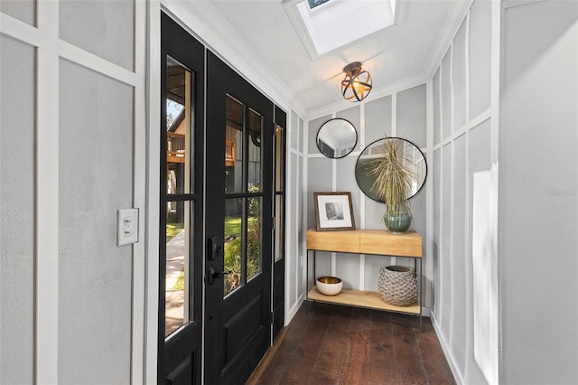 foyer entrance featuring lofted ceiling with skylight, hardwood / wood-style floors, and crown molding