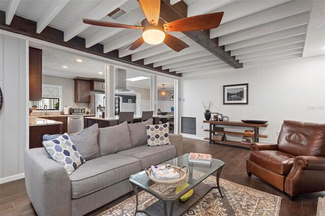 living room featuring beam ceiling, dark hardwood / wood-style floors, sink, and ceiling fan