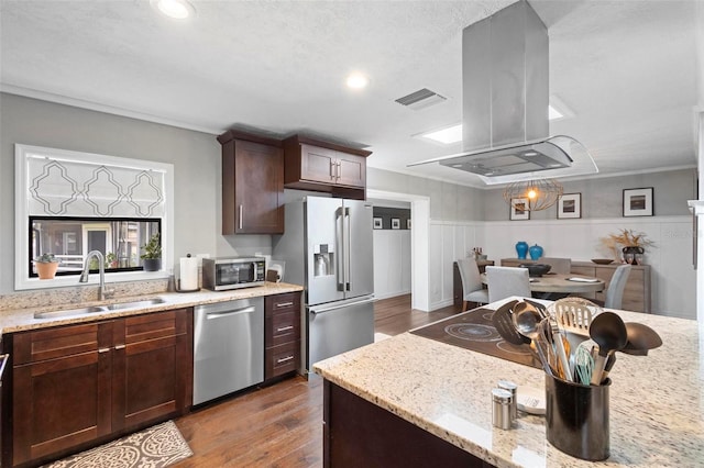 kitchen with island exhaust hood, hardwood / wood-style flooring, light stone countertops, stainless steel appliances, and sink