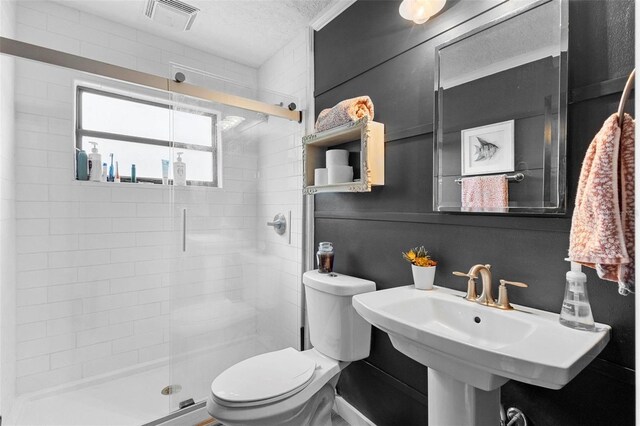 bathroom featuring toilet, walk in shower, and a textured ceiling