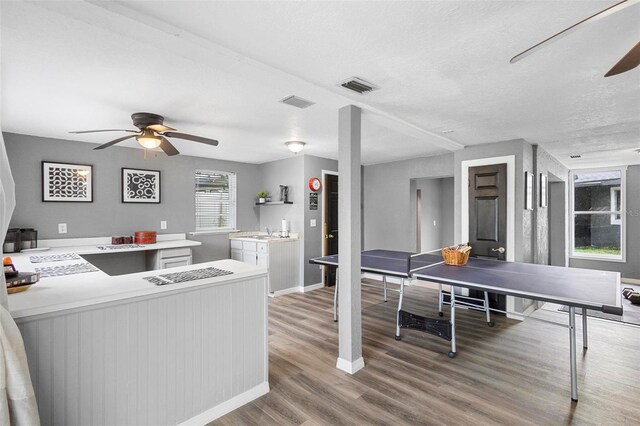 interior space featuring ceiling fan, sink, light wood-type flooring, and a textured ceiling