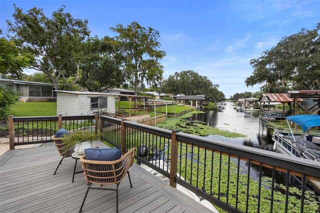 wooden deck with a lawn, a dock, and a water view