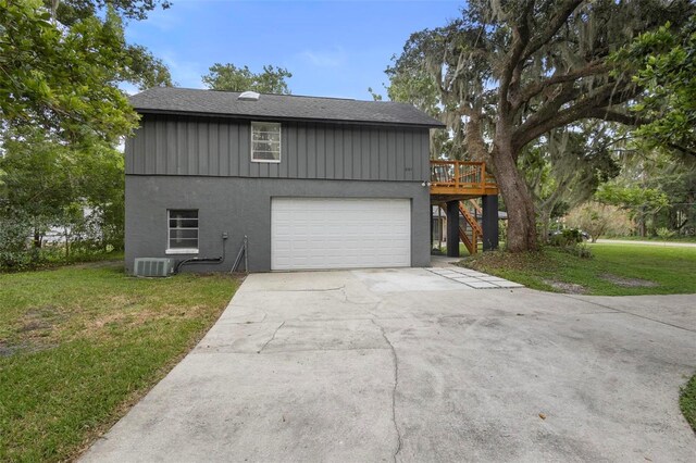 view of front facade featuring a garage, a wooden deck, a front yard, and central air condition unit