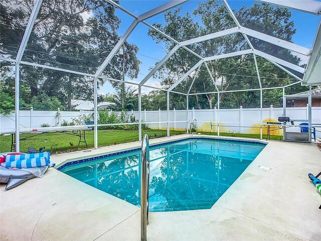 view of swimming pool with glass enclosure, a yard, and a patio area