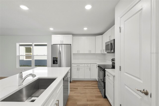 kitchen with white cabinetry, sink, appliances with stainless steel finishes, and light hardwood / wood-style flooring