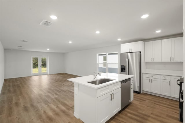 kitchen with wood-type flooring, stainless steel appliances, white cabinetry, and sink