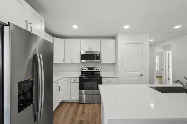 kitchen featuring white cabinets, stainless steel appliances, hardwood / wood-style flooring, and sink