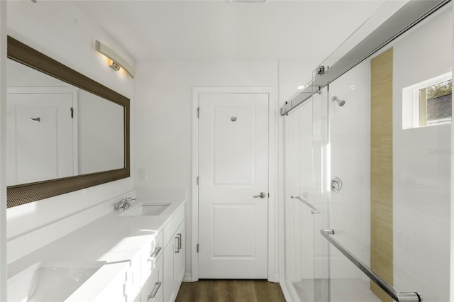 bathroom with hardwood / wood-style floors, vanity, and a shower with door