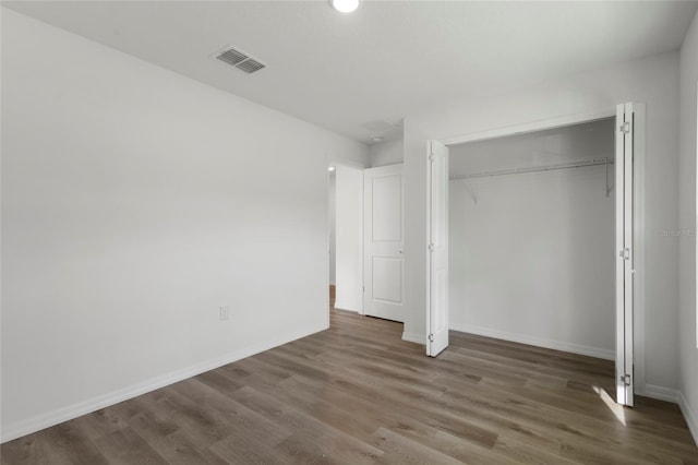 unfurnished bedroom featuring dark hardwood / wood-style flooring and a closet