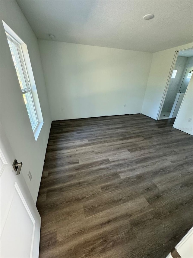 unfurnished room featuring a textured ceiling and dark hardwood / wood-style flooring