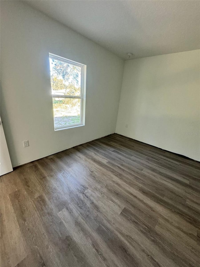 empty room with dark hardwood / wood-style floors and a textured ceiling