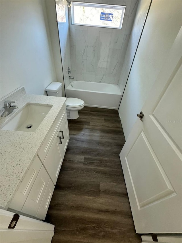 full bathroom with tiled shower / bath, vanity, wood-type flooring, and toilet