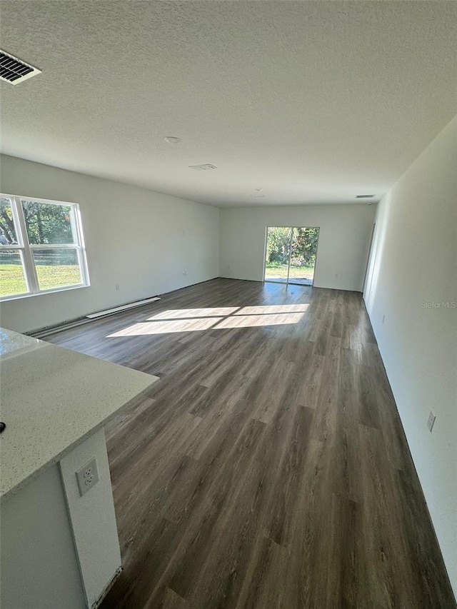 interior space featuring plenty of natural light, dark wood-type flooring, and a textured ceiling