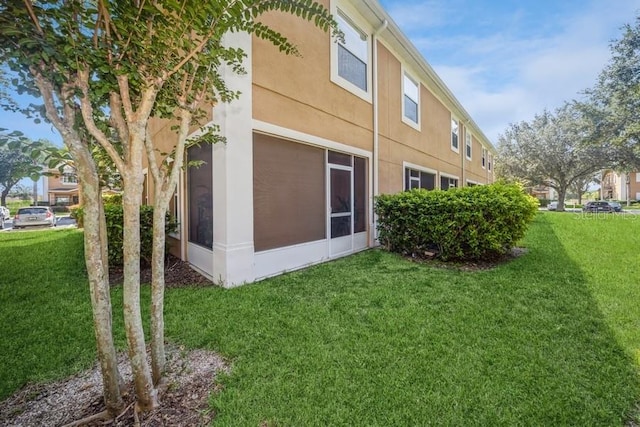 view of property exterior with a sunroom and a lawn