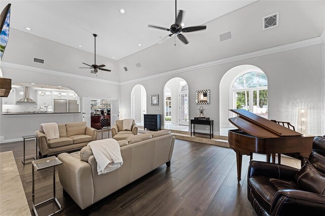 living room with a towering ceiling, dark wood-type flooring, and ceiling fan