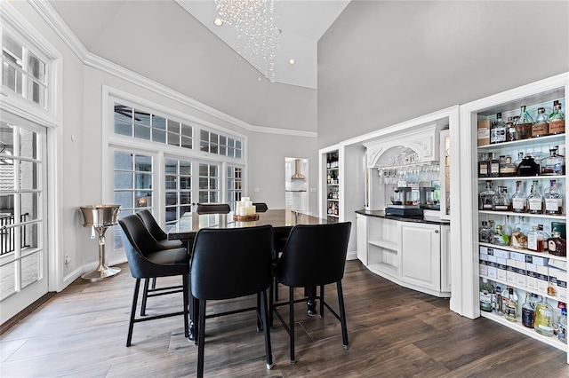 dining room featuring a towering ceiling, bar area, dark hardwood / wood-style flooring, french doors, and a chandelier