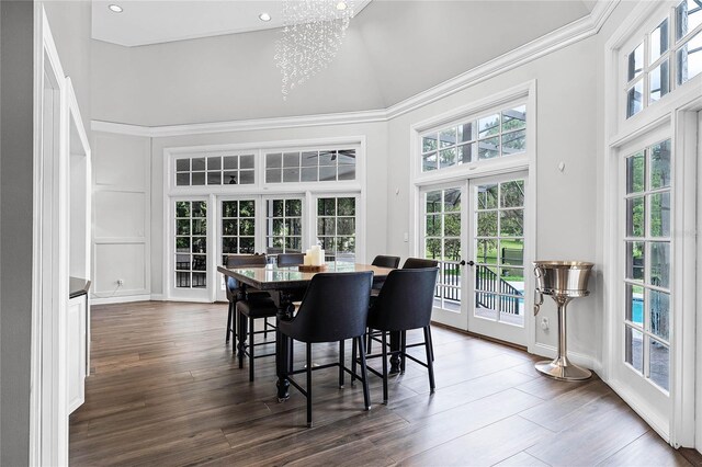 dining room with french doors, dark wood-type flooring, crown molding, a chandelier, and a towering ceiling