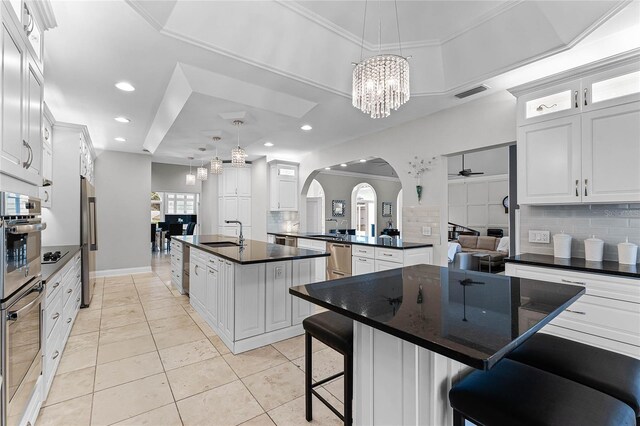 kitchen featuring white cabinets, a kitchen island with sink, and backsplash