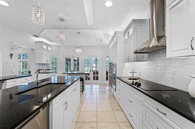 kitchen with wall chimney range hood, hanging light fixtures, french doors, and black electric stovetop