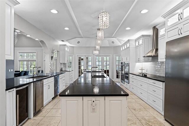 kitchen with wine cooler, wall chimney exhaust hood, a center island, pendant lighting, and stainless steel appliances