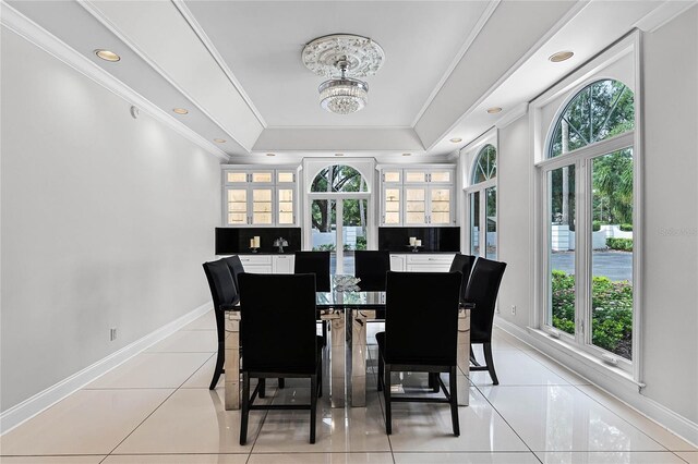 tiled dining room with crown molding, a raised ceiling, and an inviting chandelier