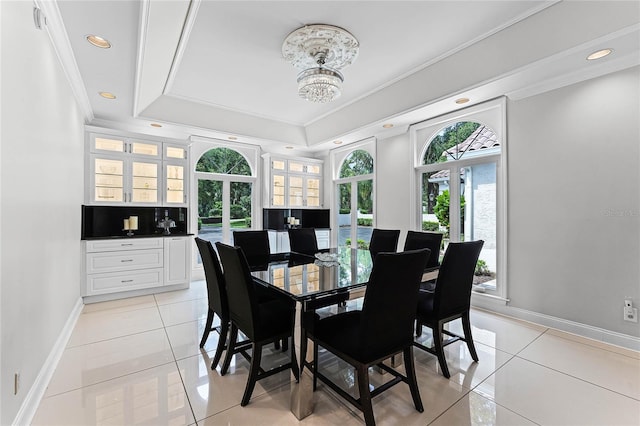 dining room featuring light tile patterned flooring, a healthy amount of sunlight, a tray ceiling, and crown molding