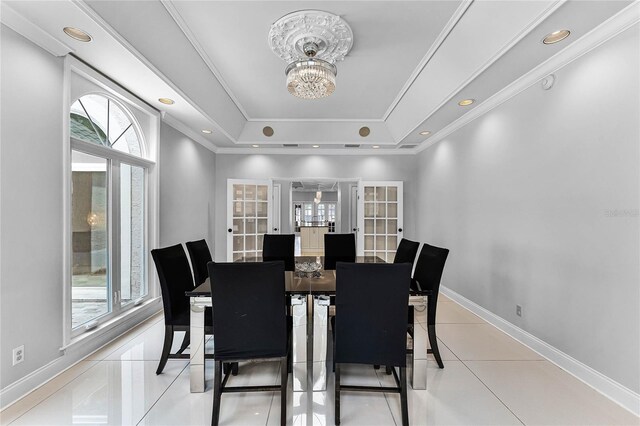 dining area with a raised ceiling, ornamental molding, plenty of natural light, and french doors