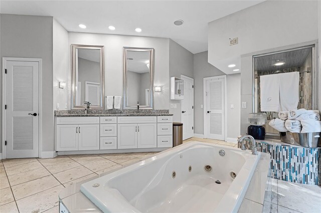 bathroom featuring tile patterned flooring, vanity, and tiled bath