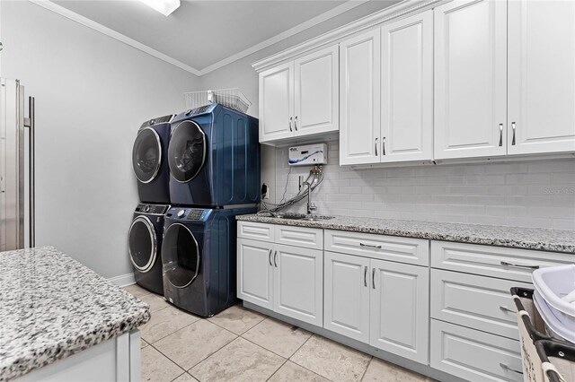 laundry area featuring cabinets, stacked washing maching and dryer, light tile patterned floors, and crown molding