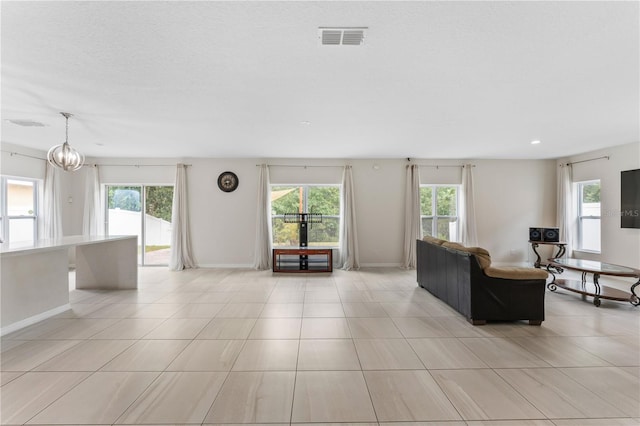 unfurnished living room with light tile patterned floors, a wealth of natural light, and an inviting chandelier