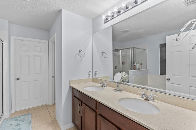 bathroom featuring a shower with door, tile patterned flooring, a textured ceiling, and vanity