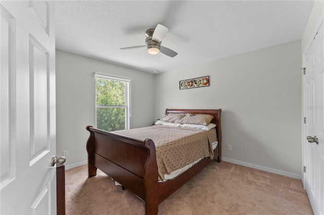 bedroom with ceiling fan, light carpet, and a textured ceiling