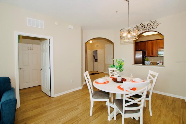 dining area with a notable chandelier and light hardwood / wood-style floors