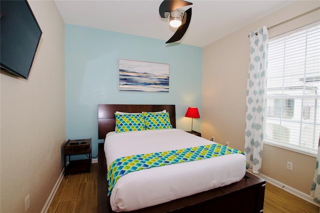 bedroom featuring hardwood / wood-style flooring, ceiling fan, and multiple windows