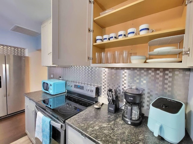 kitchen featuring white cabinetry, appliances with stainless steel finishes, light wood-type flooring, and decorative backsplash