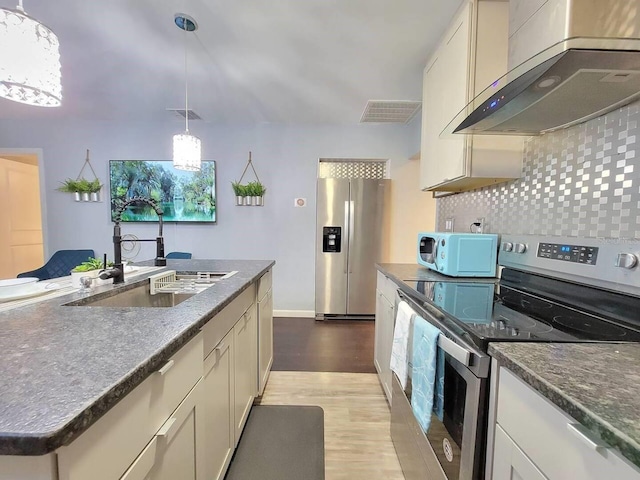 kitchen featuring sink, extractor fan, appliances with stainless steel finishes, pendant lighting, and decorative backsplash