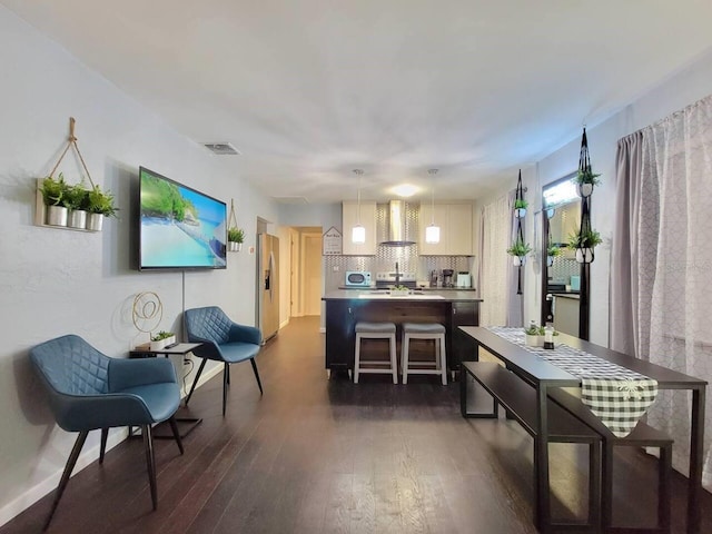 kitchen with pendant lighting, a kitchen breakfast bar, dark hardwood / wood-style flooring, stainless steel fridge with ice dispenser, and wall chimney exhaust hood