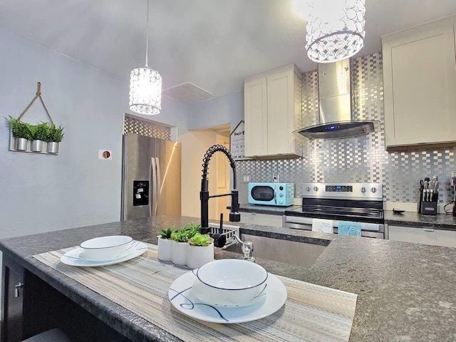 kitchen featuring wall chimney exhaust hood, stainless steel appliances, decorative light fixtures, and a chandelier