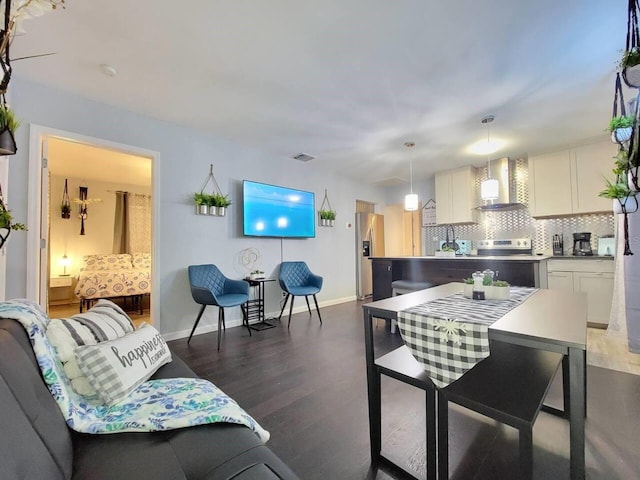 kitchen featuring pendant lighting, wall chimney exhaust hood, decorative backsplash, and white cabinets