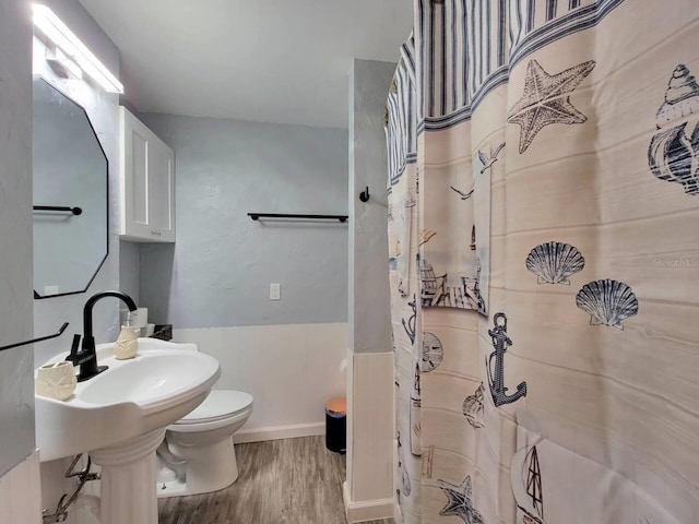 bathroom featuring sink, curtained shower, wood-type flooring, and toilet