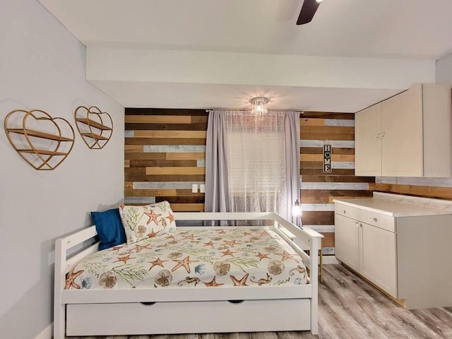 bedroom featuring light hardwood / wood-style floors and wood walls