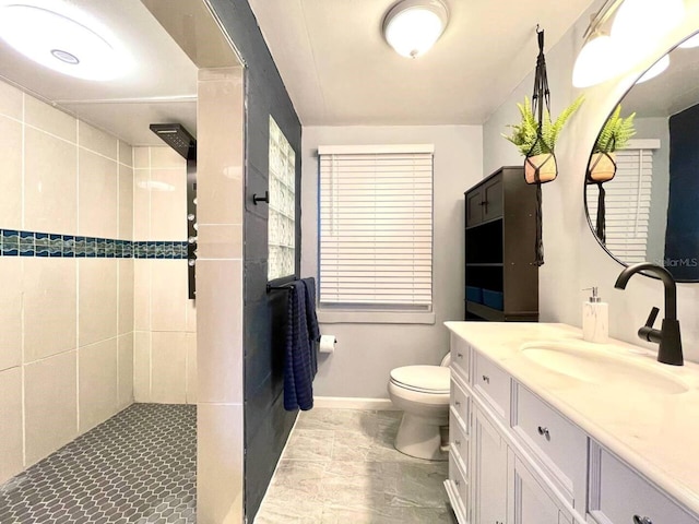 bathroom featuring a tile shower, vanity, and toilet