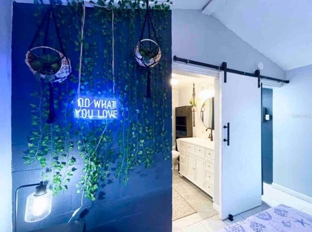 interior space featuring vaulted ceiling, a barn door, light tile patterned floors, and ensuite bathroom