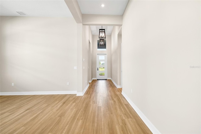 corridor featuring a notable chandelier and light hardwood / wood-style flooring