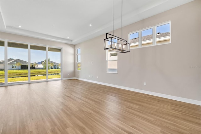 unfurnished living room with light hardwood / wood-style flooring, a chandelier, and a wealth of natural light