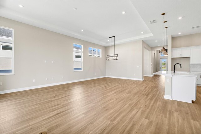 815 Liliana Dr, Deland, FL 32724 - unfurnished living room featuring a sink, a tray ceiling, light wood finished floors, recessed lighting, and baseboards