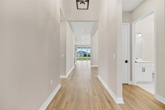 corridor featuring a notable chandelier and light wood-type flooring