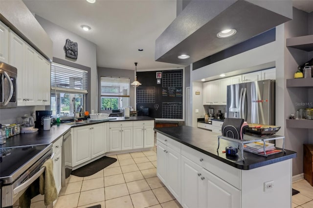 kitchen with white cabinetry, appliances with stainless steel finishes, light tile patterned floors, decorative light fixtures, and a center island