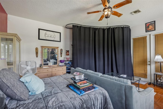 bedroom with ceiling fan, a textured ceiling, and parquet flooring